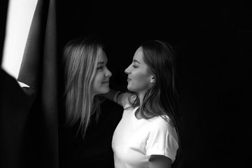 Best beautiful female friends portrait meeting each other and looking at camera with great love. Two Caucasian women having good mood and smiling expressions while posing at black background indoors.