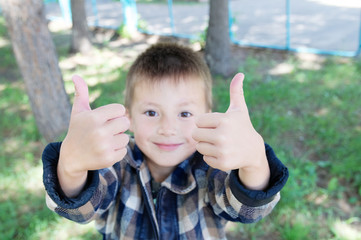 Little boy show thumb up signat summer in park