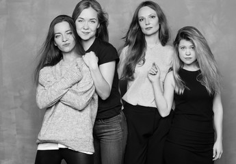 Portrait of four females having hen party photo session together. Best friends meeting, celebrating event or having rest during weekends. Attractive self-confident ladies posing at studio background.