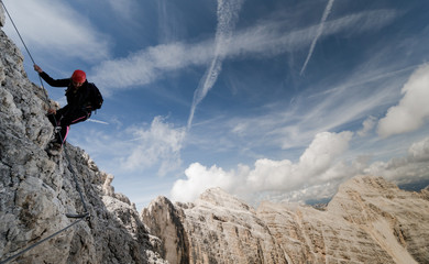 Fototapeta premium young female climber on a Via Ferrata in the Italian Dolomites with a fantastic view and background