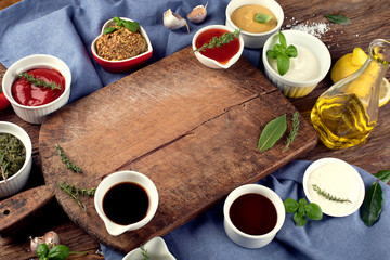 Bowls of various sauces on wooden background.