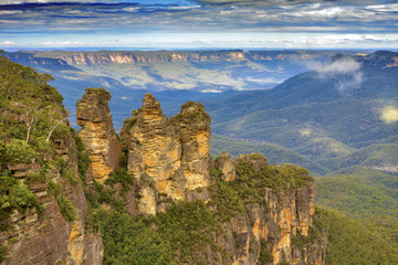 Fototapeta premium Australia - New South Wales - Unusual Three Sisters rock formation with surrounding impressive landscape of Blue Mountains National park