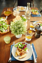 Plate on napkin with salad and roasted potatoes ans fork with knife near by on served table