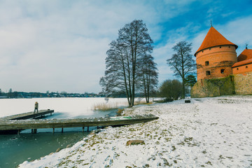 Fototapeta na wymiar Winter lake with wooden board and Trakai castle, Lithuania