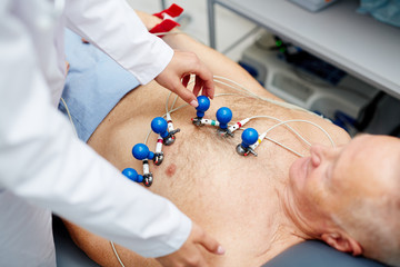 Cardiologist putting special equipment on chest of patient before making ecg