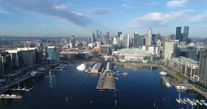Rotation in Melbourne Docklands suburb above Yarra River waters from amusement observation wheel to city CBD skyscrapers and buildings.
