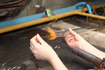 Factory of Christmas toys. The worker blows out the glass. The b