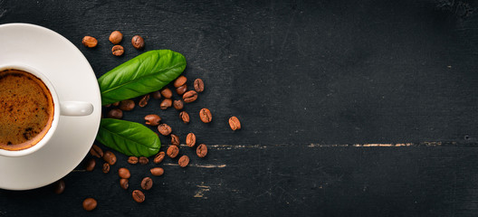 A cup of coffee and coffee beans on a wooden background. Top view. Free space for text.