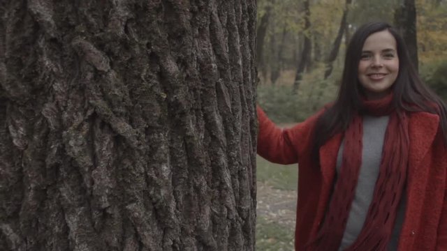 Overweight fat woman playing in autumn forest park HD slow-motion video. Obese female walking around tree, smiling and flirt 