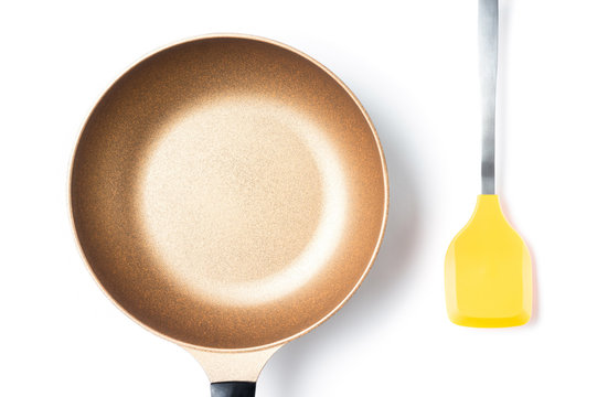 top view of metal brown pan and silicone yellow spatula on white background