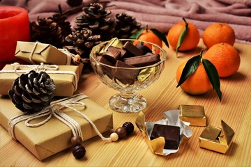 Chocolate candies, Christmas gifts and mandarin oranges on the table.