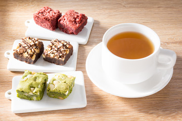 three sort of mini brownies with hot tea cup on wood table