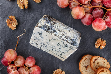 Closeup of Gorgonzola cheese and vibrant grapes on black
