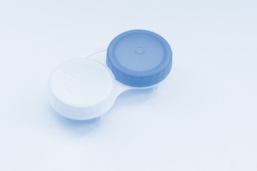 Contact lens case on light blue background. Selective focus.