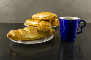 Croissant and a mug of black coffee for breakfast.