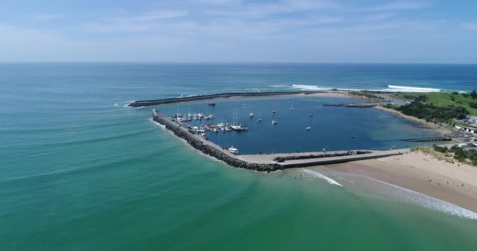 Apollo bay town harboured marine enclosed from open sea at the tip of sandy beach from above.
