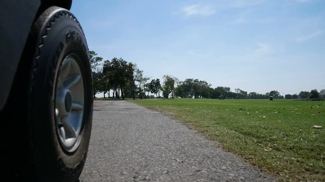 Low short near ground : Driving golf cart in a golf course in Thailand. Beautiful, bright sunny day. Short seeing wheel of golf cart on part and other golf cart in the fairway.