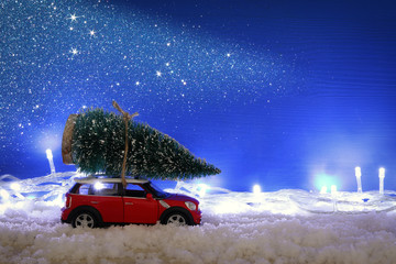 Fototapeta na wymiar Red car carrying a christmas tree over the snow.
