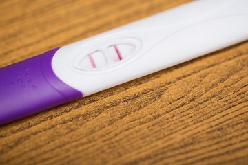 Positive White Plastic Pregnancy Test Display results for pregnancy. on wooden Background.