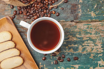 Warm coffee cup with roasted beans on rustic table