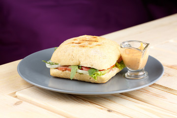 Panini with sause in the grey plate on the wooden table