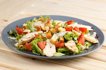 Caesar salad in the grey plate on the wooden table
