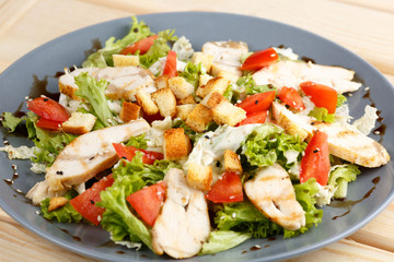 Caesar salad in the grey plate on the wooden table