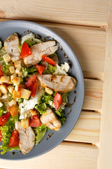 Caesar salad in the grey plate on the wooden table