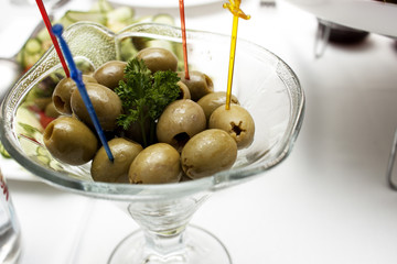 Spanish olives in a glass pial on a white table