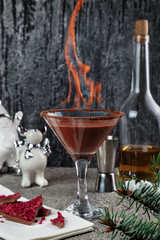 burning chocolate shake in a glass on a high stem, decorated with cocoa and chocolate with raspberries