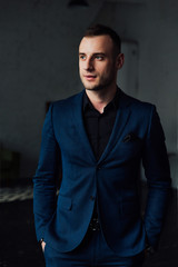 Fototapeta premium Young attractive and confident businessman in blue suit and black tie.