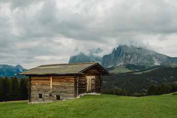 Fototapeta na wymiar Old cabin with moody view to mountain Plattkofel and Langkofel on Alpe di Siusi in the Dolomites