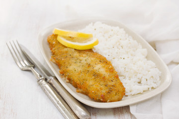 fried fish with lemon and boiled rice on dish