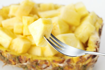piece of pineapple on fork and choped pineapple at back stage