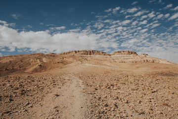Rocky road on desert in Israel. Ramon crater blue sky landscape.