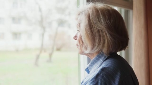 Sad elderly woman looking out the window