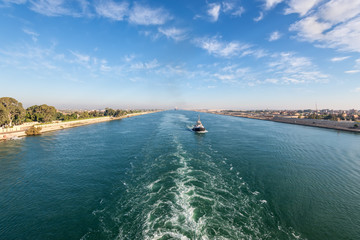Ship passing through the Suez Canal in Egypt. Tugboat accompanies the ships.