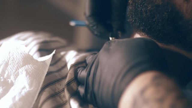 The barber shaves his head, mustache and beard to the man in the barbershop. The stylist uses a classic sharp razor, neatly shaving the client.