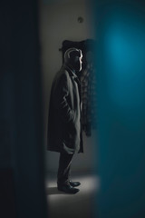 Fototapeta na wymiar Man in long coat and woolen cap standing in hallway.