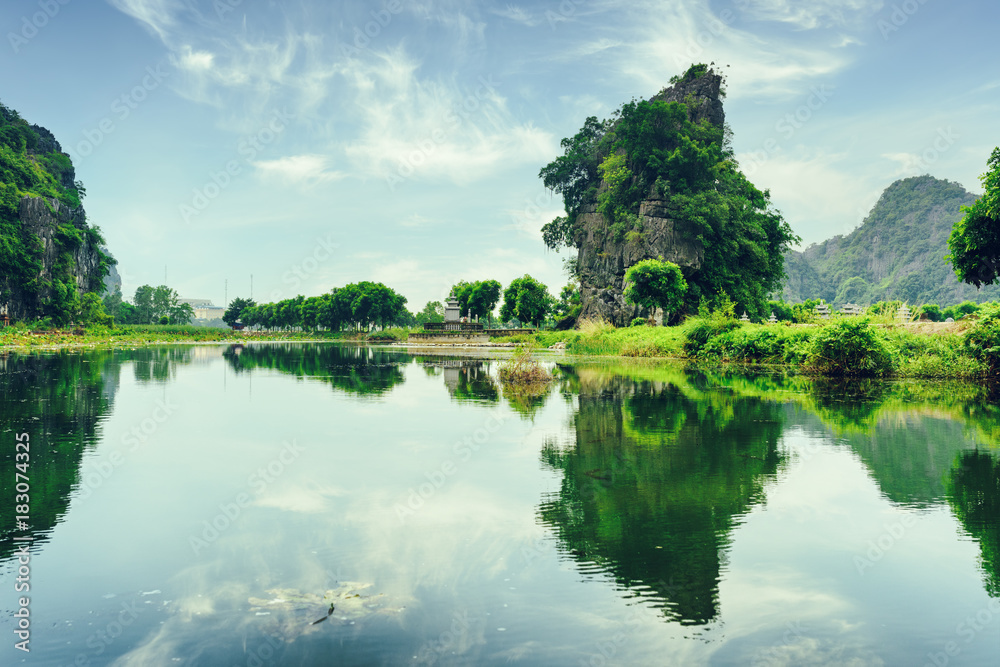 Wall mural karst towers and green trees reflected in water. toned image