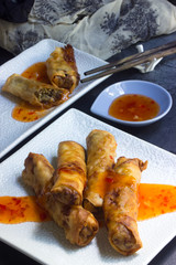 Frühlingsrollen gefüllt mit Chillisauce auf einem Teller mit Essstäbchen