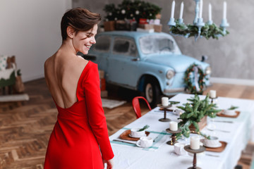 Young girl in a red dress is posing on a christmas decored interior