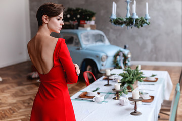 Young girl in a red dress is posing on a christmas decored interior