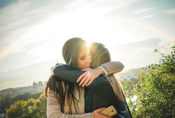 Happy meeting of two friends hugging at sunset outdoor - Pleasant moment of young sisters embracing...
