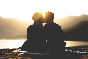 Romantic young couple kissing on the beach on sunset - Silhouette of teens lovers at the beginning...