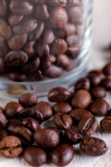 Coffee beans or grain in jar on white wooden background. Macro.