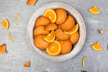 Cookies and orange citrus fruit on metal plate on grey background. Flat lay