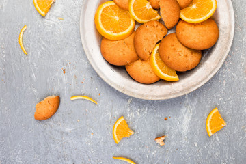 Cookies and orange citrus fruit on metal plate on grey background. Flat lay