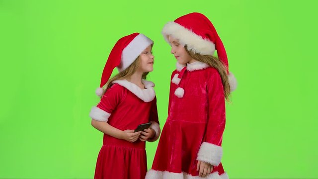 Two children in New Year costumes do selfie on the phone. Green screen. Slow motion