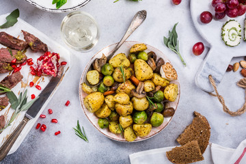 Fried potatoes with vegetables and herbs on gray stone background. Healthy food concept. Top view, flat lay.